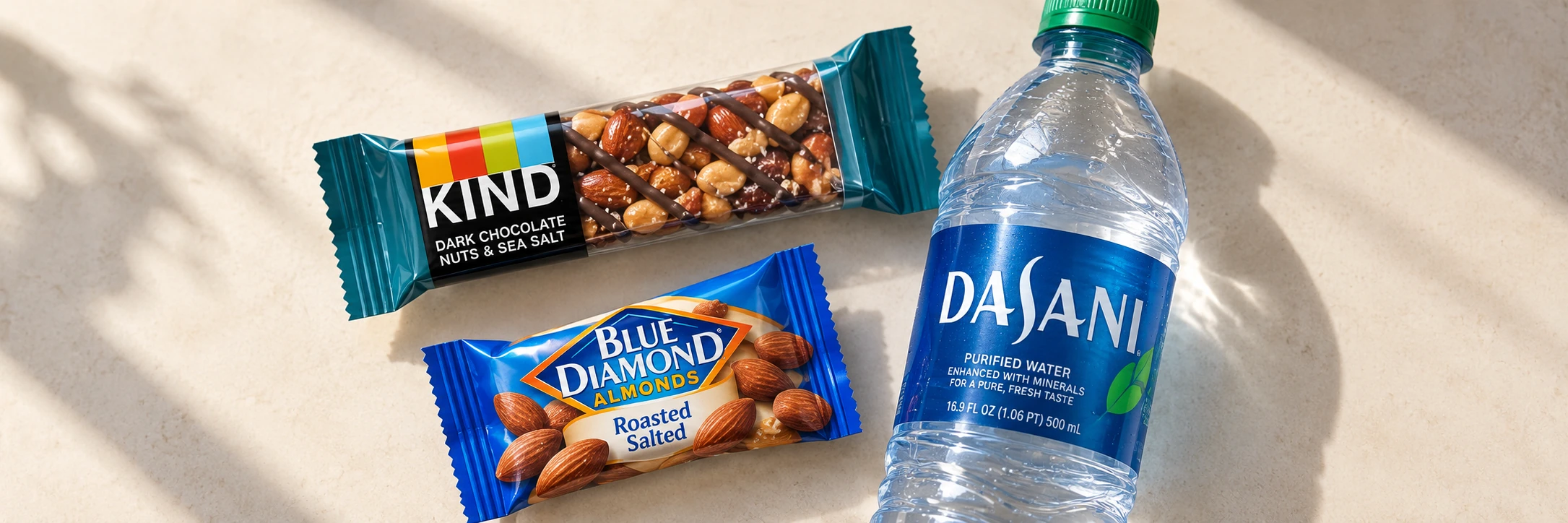 KIND bar, Blue Diamond almonds, and Dasani water on a sunlit table